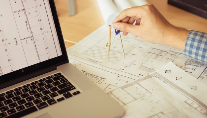Architect using a drafting compass over commercial floor plans