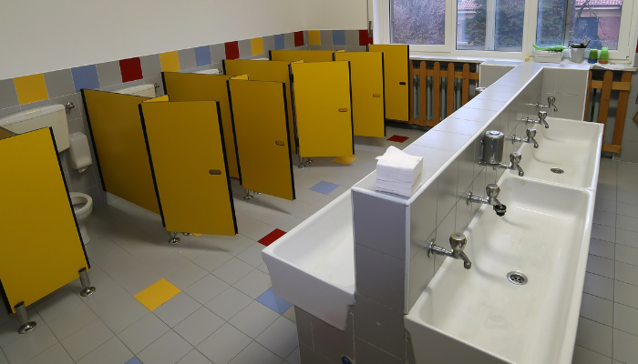 school restroom with stall partitions and a row of sinks where dispensers require regular maintenance